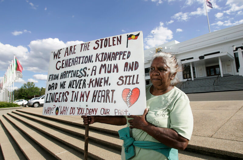 Aboriginal Elder Nancy Hill-Wood from Sydney holds a protest banner in front of Old Parliamnt House on February 11, 2008 in Canberra, Australia. [Andrew Sheargold/Getty Images]